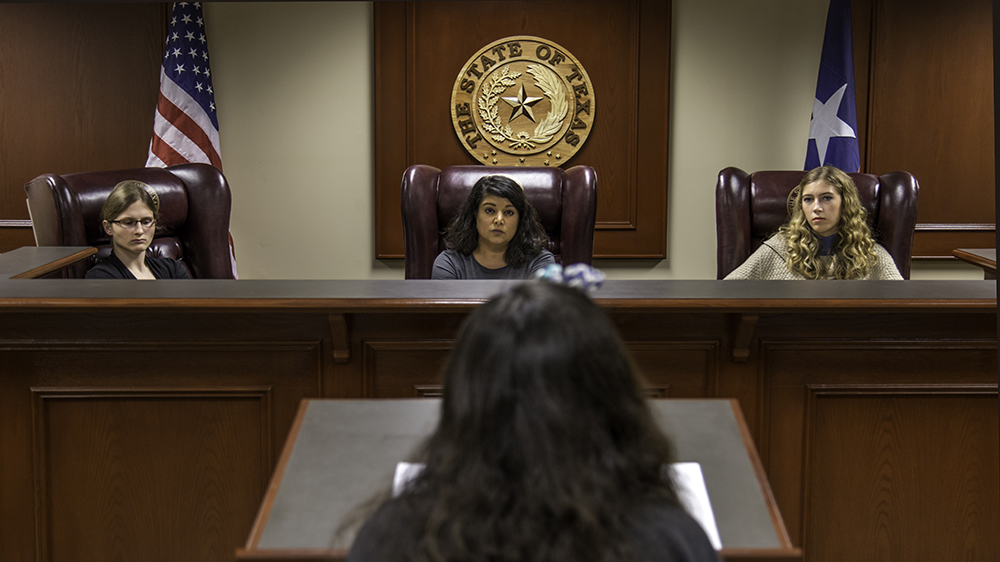 Students participate in moot court activities in a wood-paneled courtroom. 